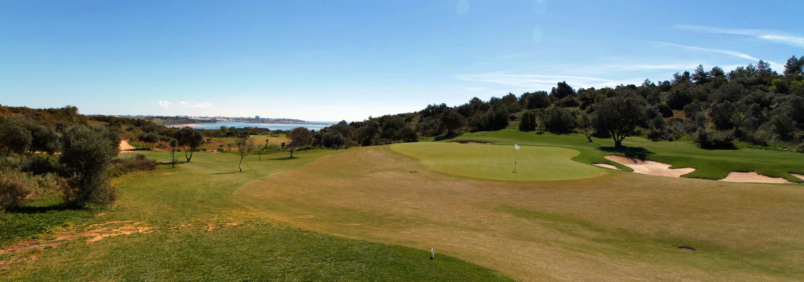 A putting green and bunkers at Palmares, with the coast near Lagos beyond